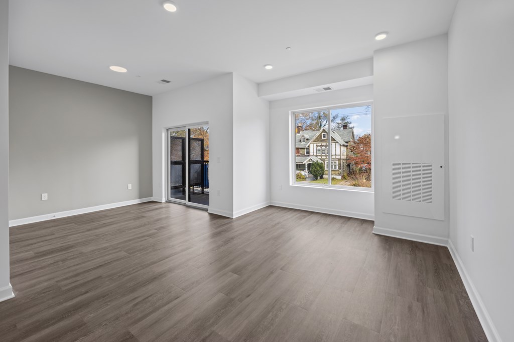 A room with wooden flooring and a large window showing a house. at The Lumos Apartments, Ohio, 44106