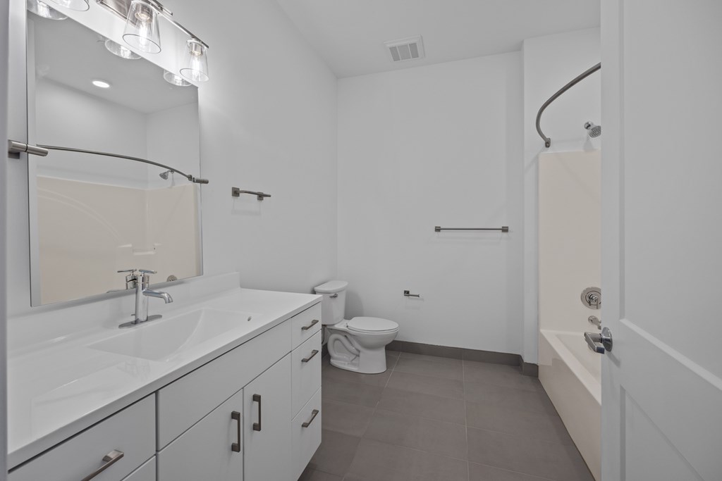A white bathroom with a sink, toilet, and bathtub. at The Lumos Apartments, Cleveland 44106