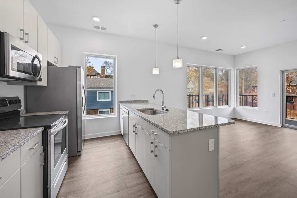 A modern kitchen with a large island and stainless steel appliances at The Lumos Apartments, Cleveland 44106