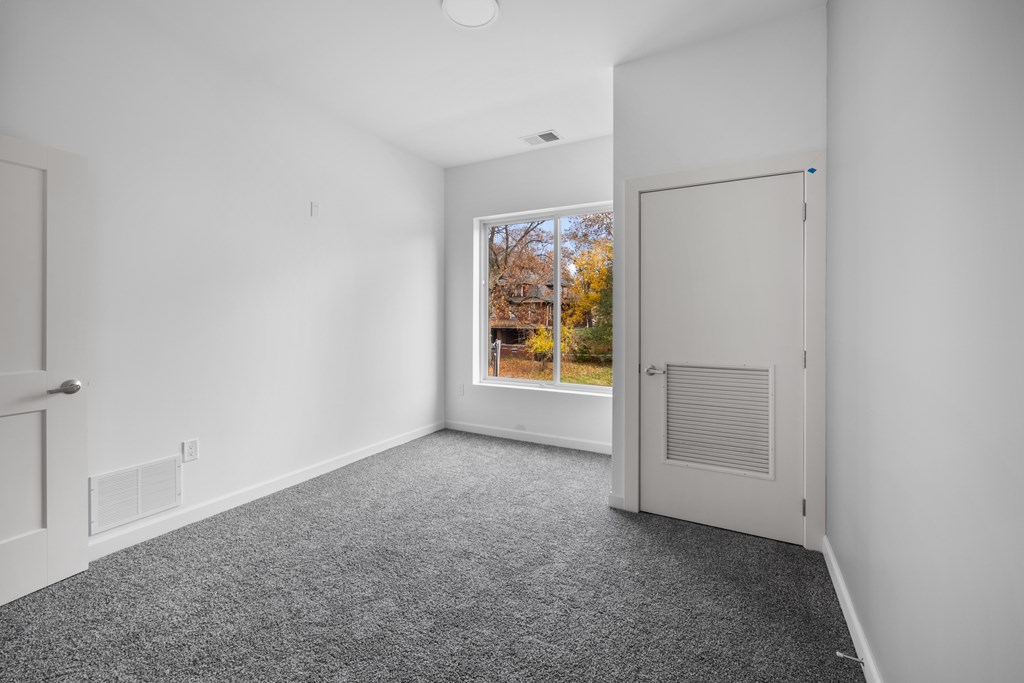 A room with a grey carpet and a white door. at The Lumos Apartments, Ohio