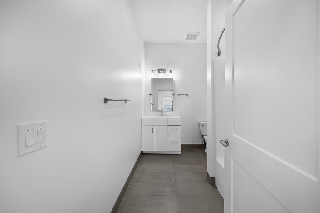 A white bathroom with a toilet, sink, and cabinet. at The Lumos Apartments, Cleveland, OH, 44106