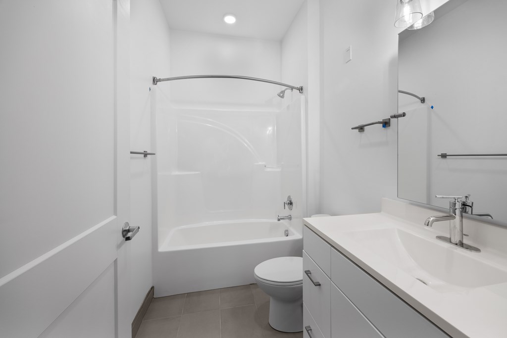 A white bathroom with a toilet, sink, and bathtub. at The Lumos Apartments, Cleveland, OH