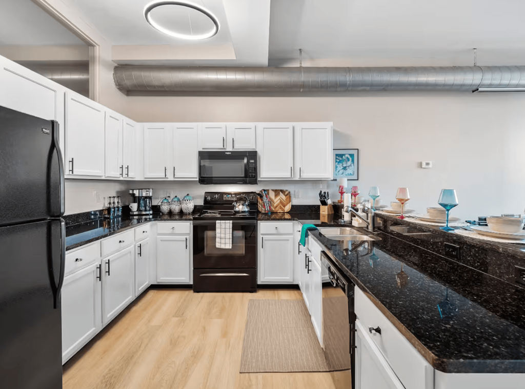 A kitchen with black countertops and white cabinets.