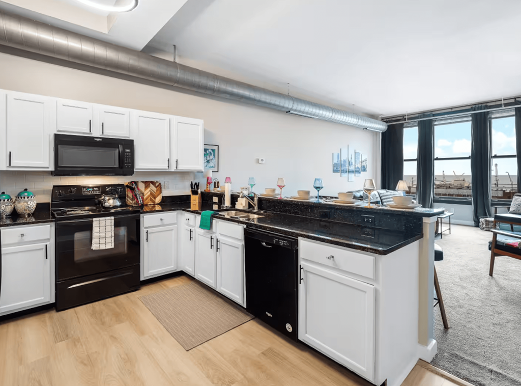 A kitchen with black countertops and white cabinets.