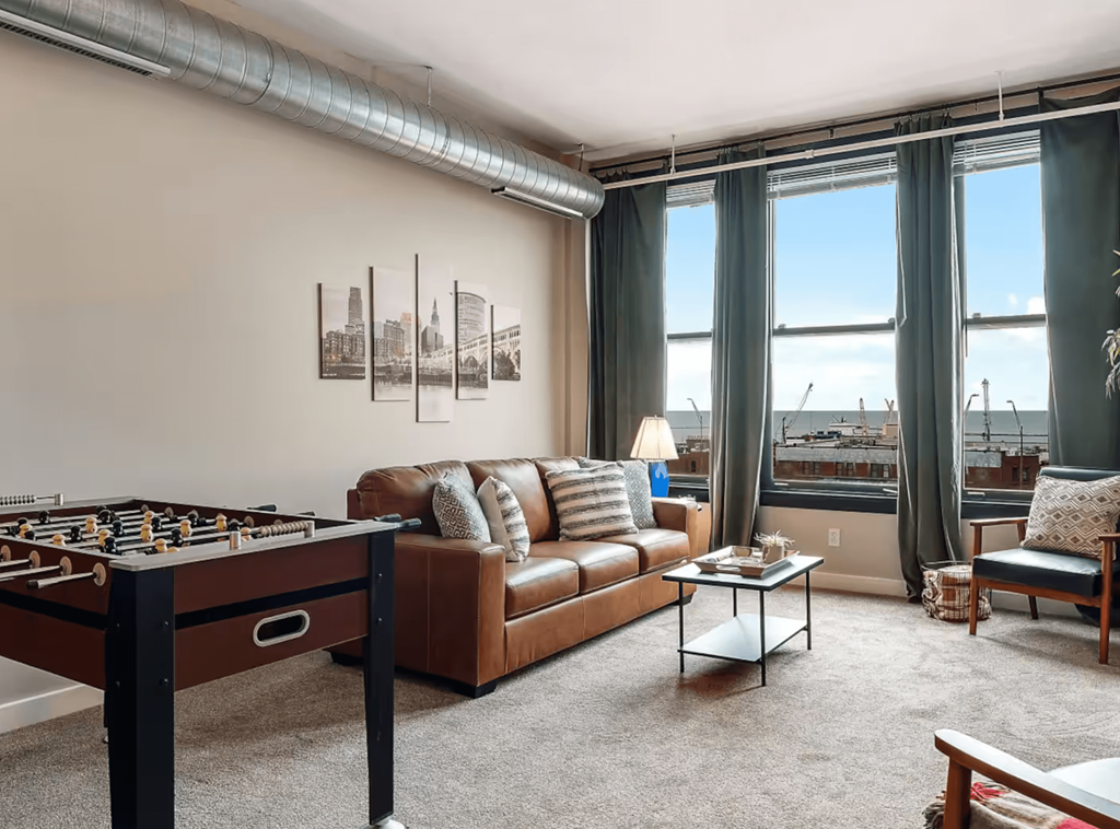 A living room with a foosball table, couch, and pictures on the wall.