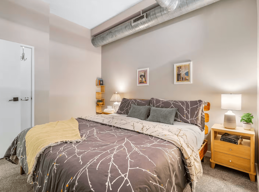 A bedroom with a bed, nightstand, and wall art.