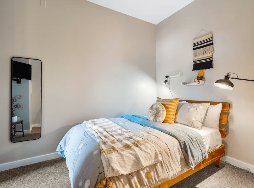 A bedroom with a bed covered in a blue and white comforter.
