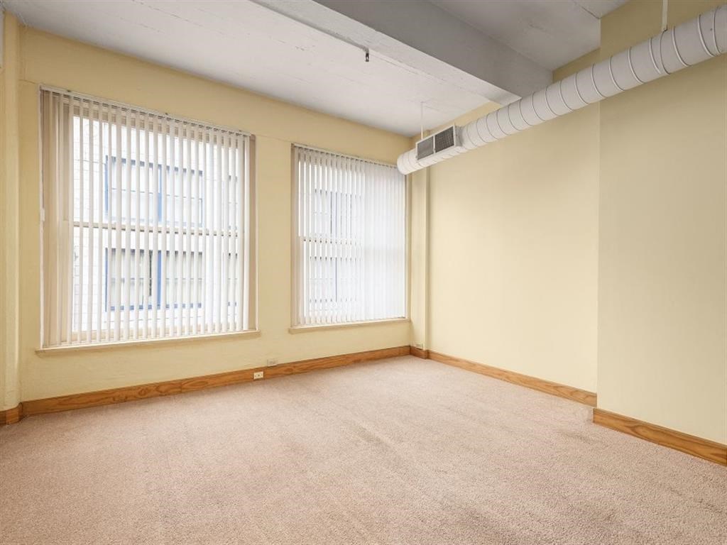 an empty room with three windows and a white pipe