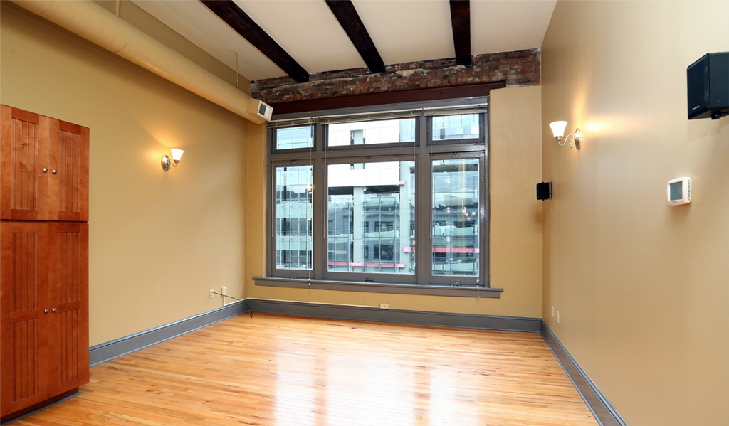 an empty room with a large window and wooden floors