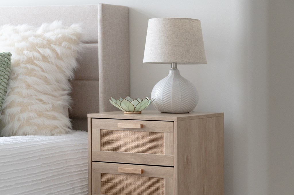 a nightstand with a lamp and a white vase on it in a bedroom in Rocky River, OH 44116