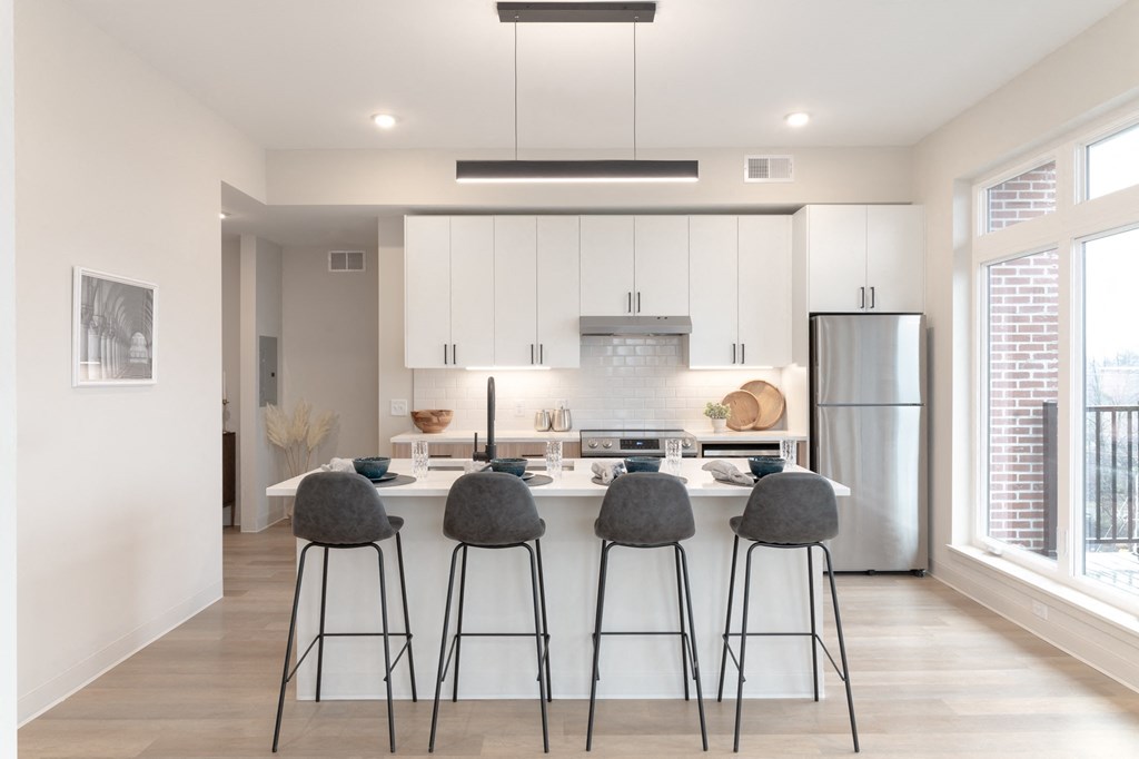 a kitchen with white cabinets and a bar with four stools in Rocky River, OH 44116