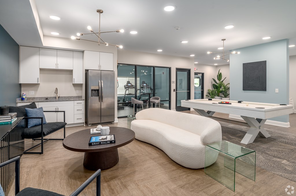 A modern kitchen with a breakfast bar and a living room area with a sofa and a coffee table. at Park Lamont Townhomes Apartments, Cleveland