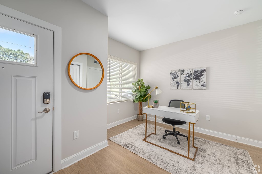 A white door with a round mirror on the wall next to a desk with a plant on it. at Park Lamont Townhomes Apartments, Cleveland