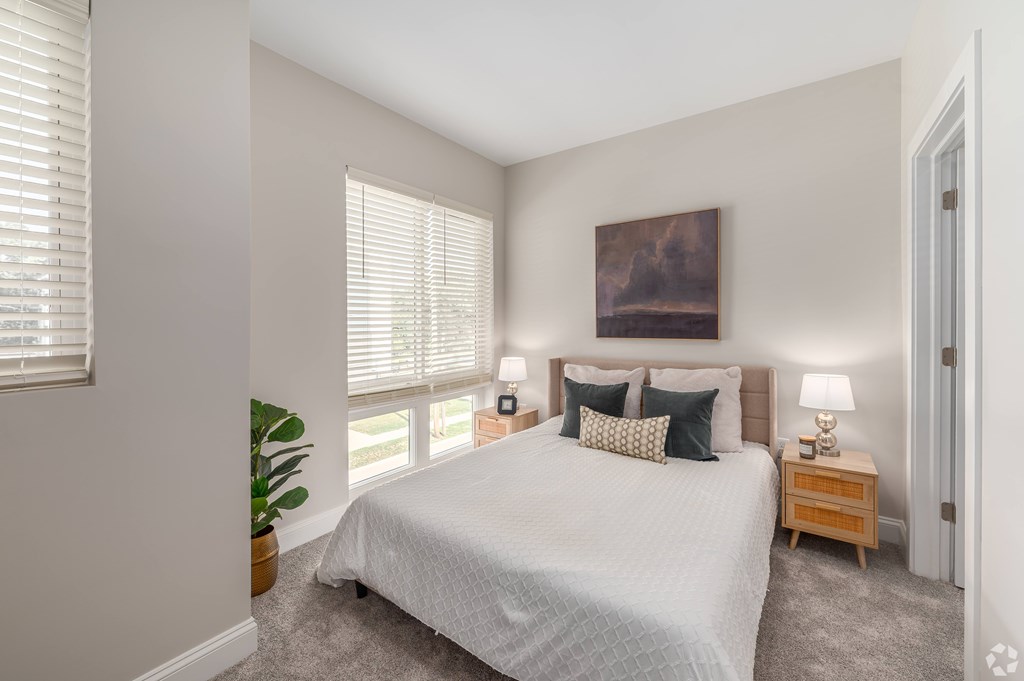 A bedroom with a large bed, a nightstand, and a painting on the wall. at Park Lamont Townhomes Apartments, Cleveland, OH