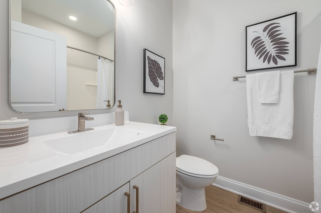 A white bathroom with a toilet, sink, and mirror. at Park Lamont Townhomes Apartments, Cleveland, OH, 44106
