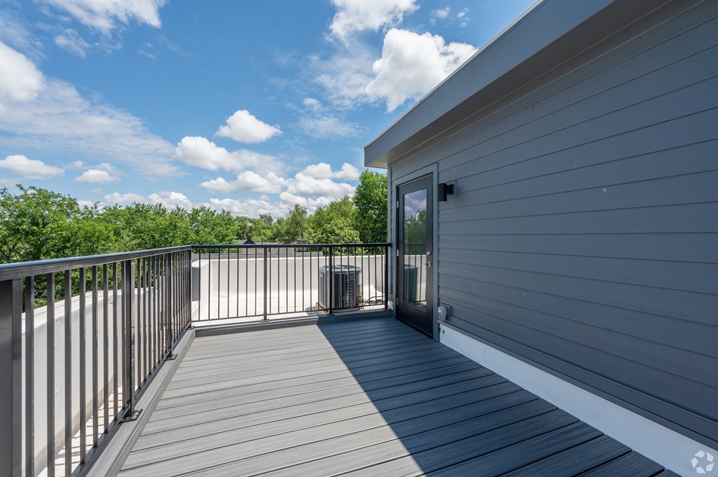 A balcony with a railing and a door leading to a house. at Park Lamont Townhomes Apartments, Ohio