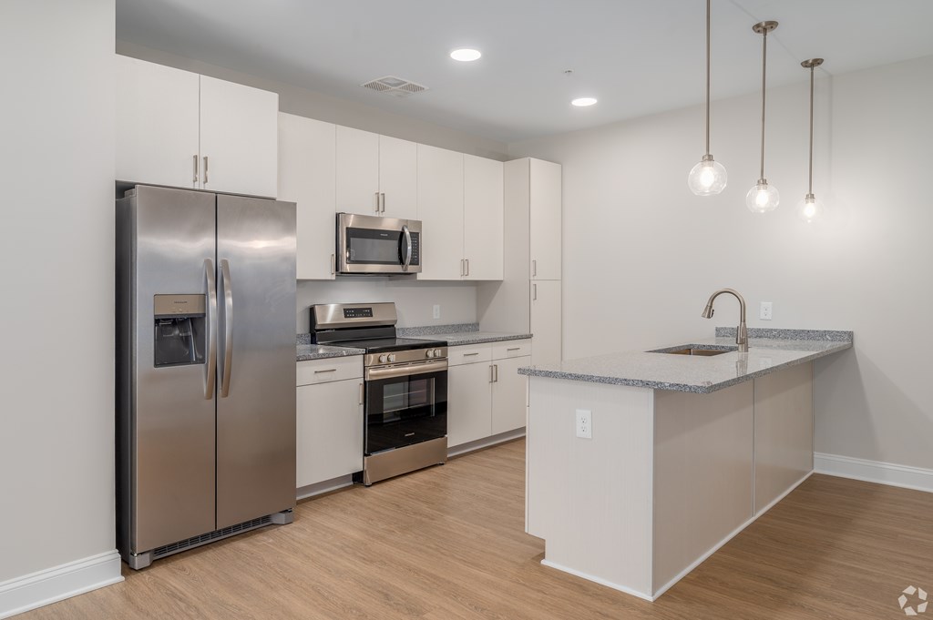 A modern kitchen with stainless steel appliances and wooden flooring. at Park Lamont Townhomes Apartments, Cleveland