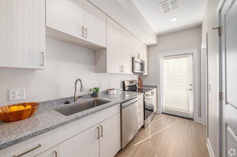 A modern kitchen with white cabinets and a granite countertop.