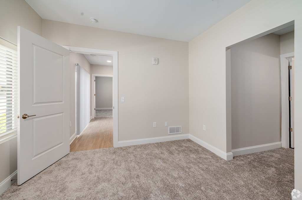 A room with a carpeted floor and a door on the left. at Park Lamont Townhomes Apartments, Cleveland, OH, 44106