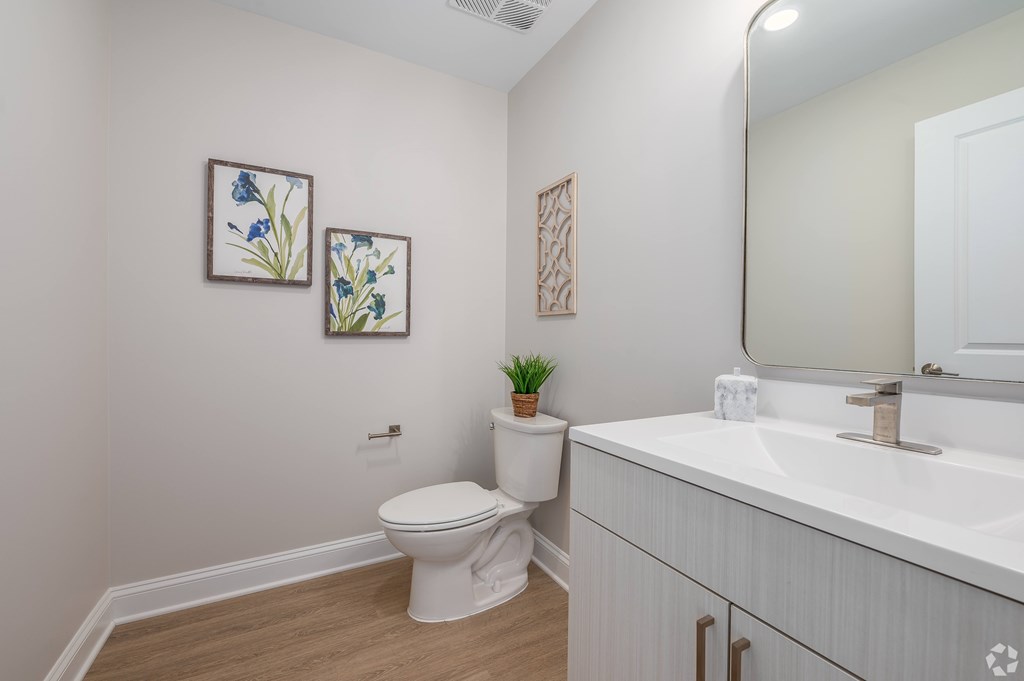 A white toilet sits next to a white sink in a small bathroom. at Park Lamont Townhomes Apartments, Cleveland, Ohio
