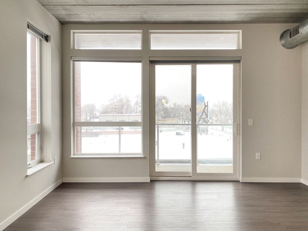 an empty living room with large windows and wood floors