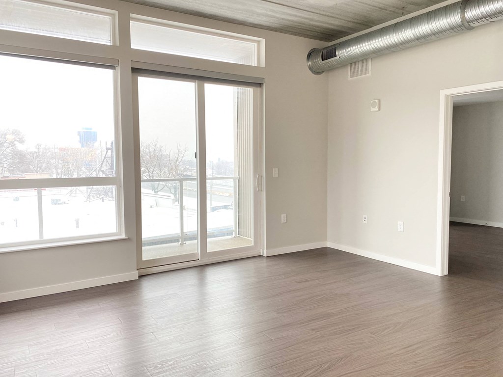 an empty living room with sliding glass doors and wood floors