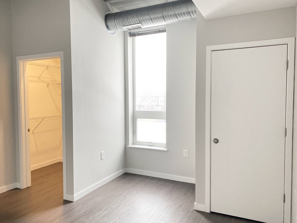 an empty room with a door to a closet and a window