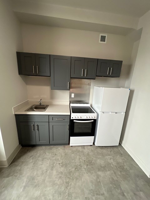 A kitchen with a white fridge and a sink.