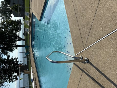 A pool with a diving board and a metal ladder.