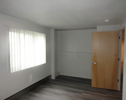 A room with a wooden door and a window with blinds.