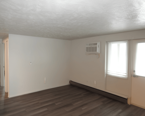 A room with a white ceiling, a window, and a wooden floor.