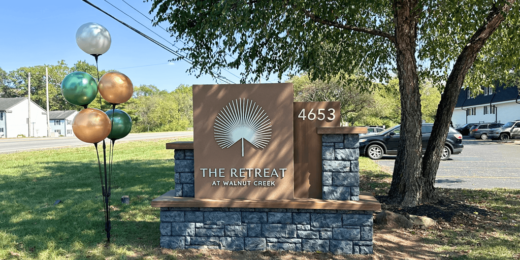 A sign for The Retreat at Walnut Creek stands in front of a parking lot.