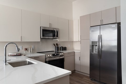 A modern kitchen with a stainless steel refrigerator and white countertops.