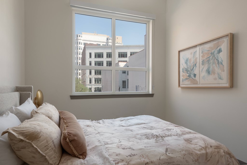 A bedroom with a large bed and a framed artwork on the wall.