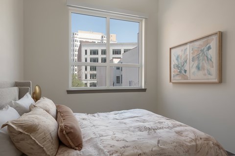 A bedroom with a large bed and a framed artwork on the wall.