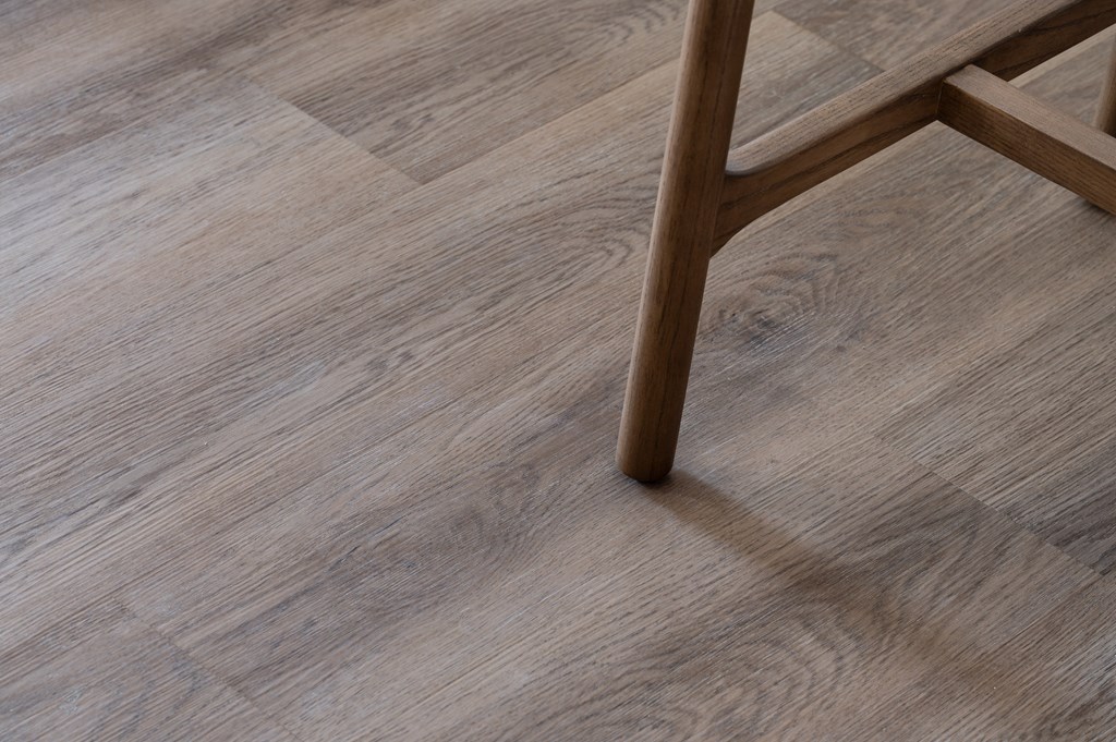 A wooden chair leg is on a wooden floor.