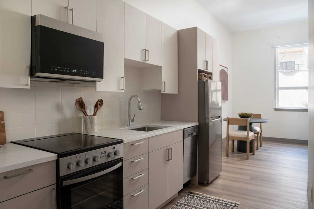 A modern kitchen with a black stove top oven and white cabinets.