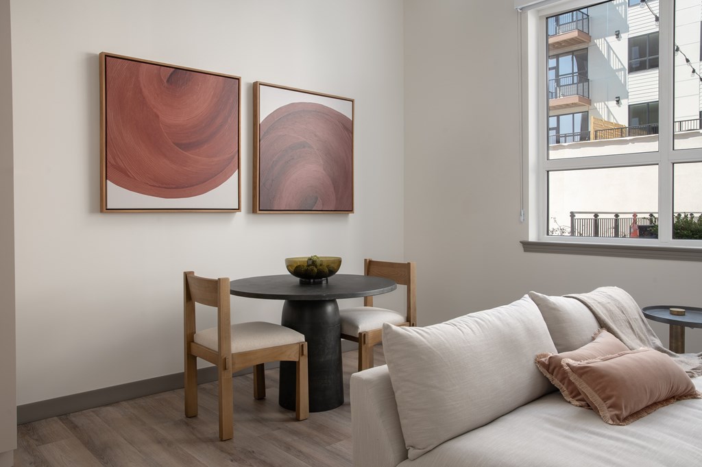 A living room with a table and chairs and two paintings on the wall.