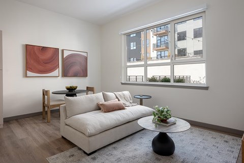 A living room with a white couch, a small table, and two paintings on the wall.