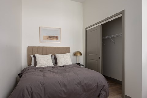 A bedroom with a bed, pillows, a lamp, and a painting on the wall.