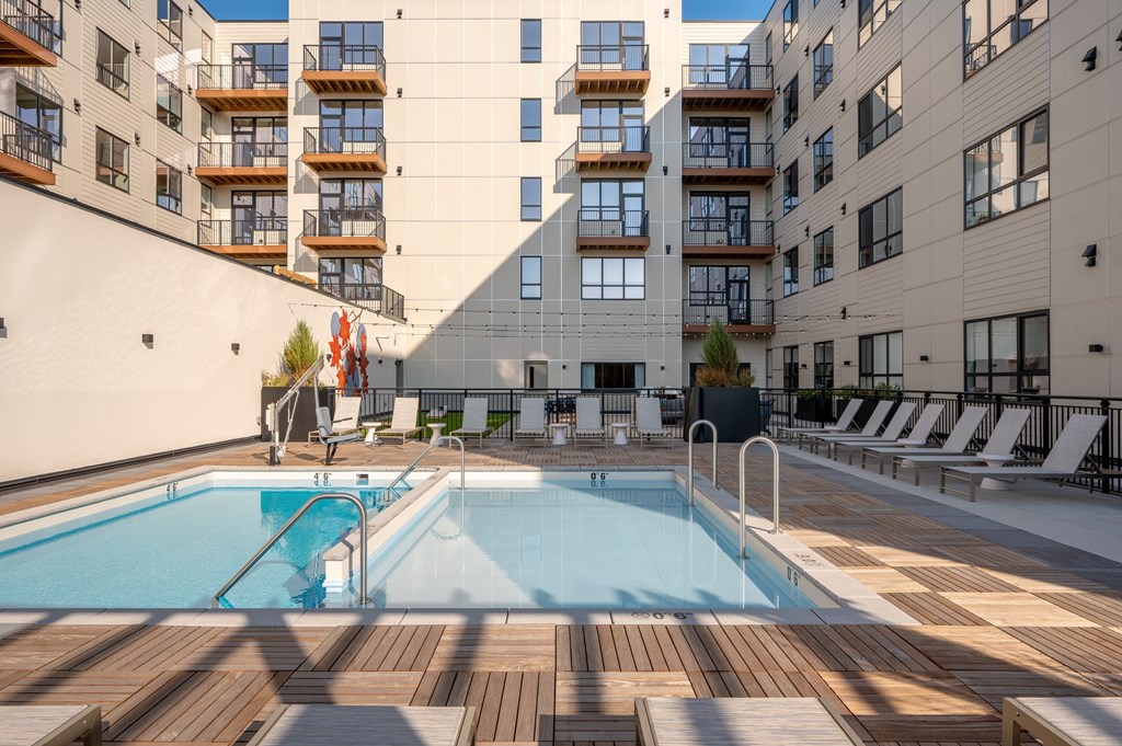 A large outdoor swimming pool surrounded by wooden decking and lounge chairs.