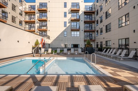 A large outdoor swimming pool surrounded by wooden decking and lounge chairs.