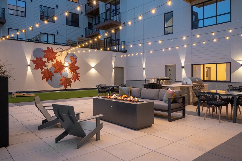 A patio with a table and chairs is lit by string lights.