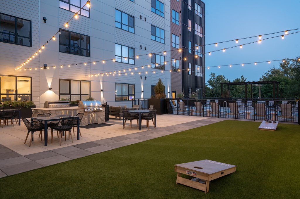 A rooftop deck with a lawn, a table and chairs, and a pool.