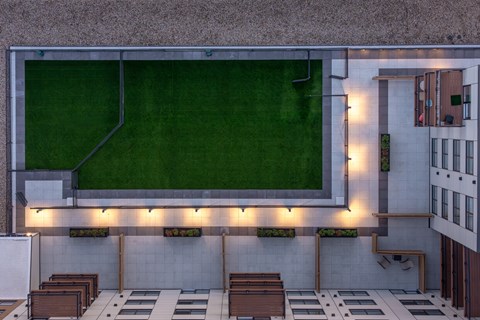 A modern outdoor seating area with wooden tables and benches.