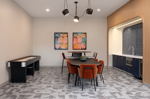 A room with a pool table, a dining table with chairs, and two paintings on the wall.