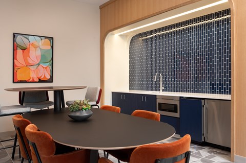 A modern dining room with a round table and orange chairs.