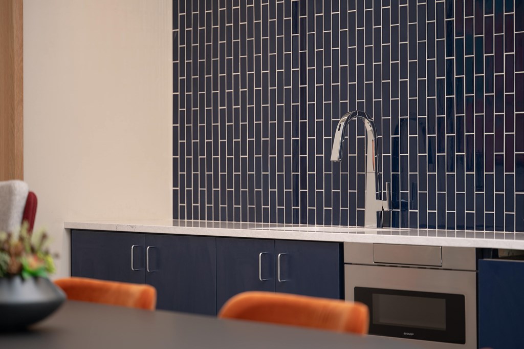 A kitchen with a blue tiled backsplash and a modern sink.