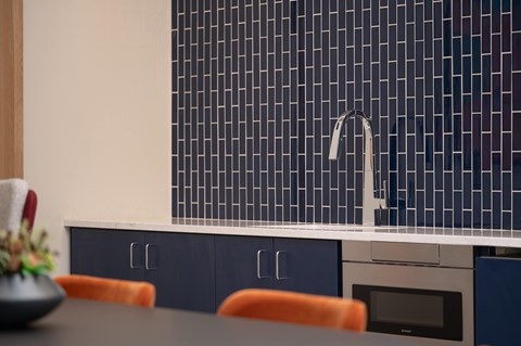 A kitchen with a blue tiled backsplash and a modern sink.
