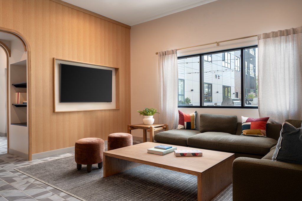 A living room with a brown couch, a coffee table, and a flat screen TV mounted on the wall.